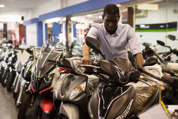 Afro american man is shopping and choosing new motobike in moto store