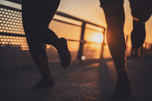Body part silhouettes of couple who is jogging in the city in sunset.