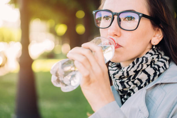 istock Girl with glasses drinks mineral water from a plastic bottle. 1263623797