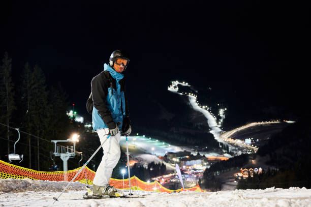 istock Male skier standing on snowy hill at night. 1263627739