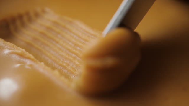 Peanut Butter Background. Delicious and Hearty Breakfast Nut Cream. Closeup Creamy Smooth Peanut Butter. Healthy Organic Food. Slow Motion. Caramel Macro Shot.