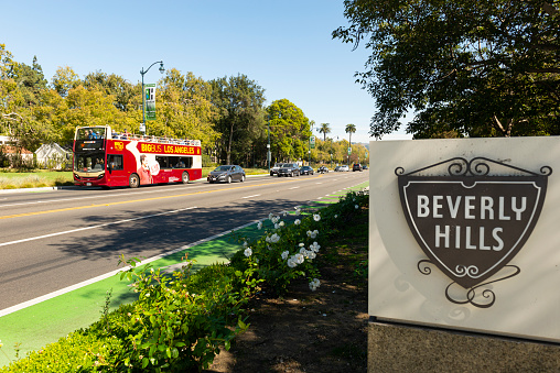 Beverly Hills, California, United States - October 20, 2019: View of a Beverly Hills sign, along with nature, the bicycle lane, cars, and a tour bus in Beverly Hills, California - United States