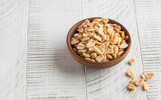 Salted peanuts in a wooden bowl on a light wooden table. Healthy snacks, healthy food. Nuts. Copy space. High quality photo