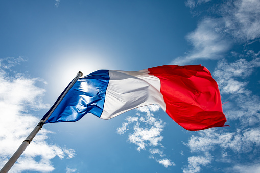 French flag flying against a bright sun
