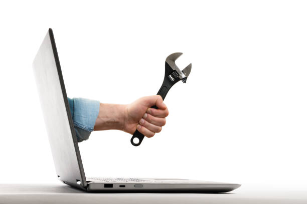 Concept of technical support. The human hand with black wrench stick out of a laptop screen. Concept of technical support. Isolated on white. telegram machine photos stock pictures, royalty-free photos & images