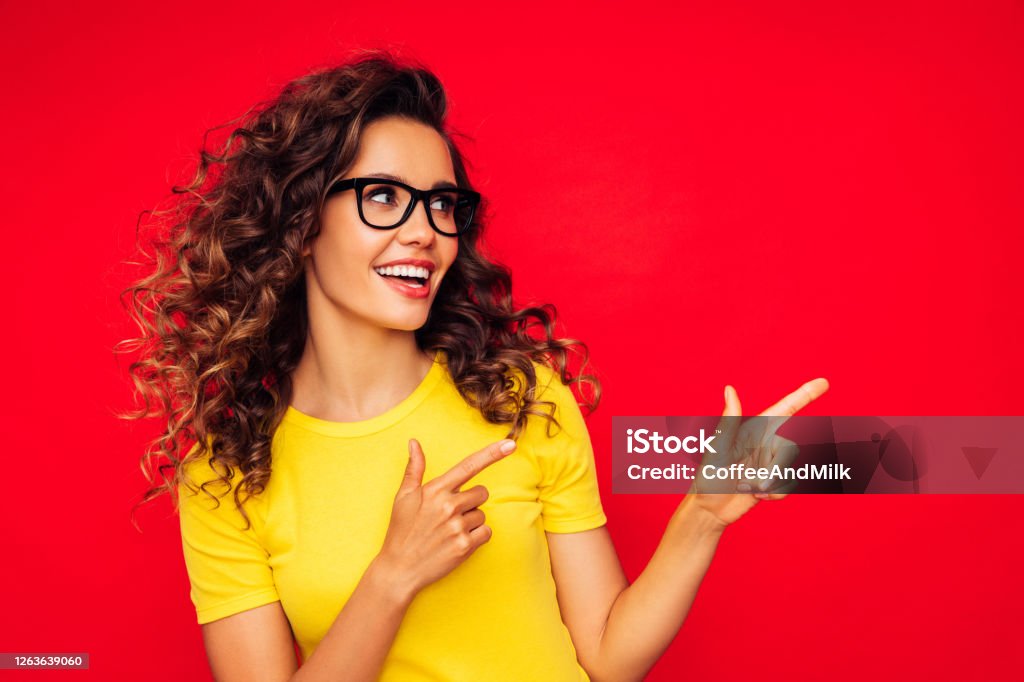 Beautiful girl on the red background showing right direction with her fingers Happiness Stock Photo