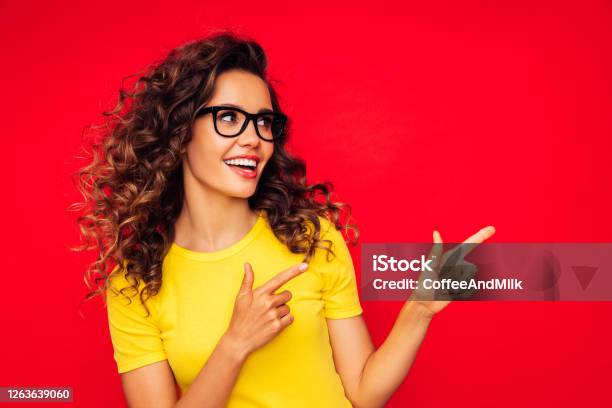Beautiful Girl On The Red Background Showing Right Direction With Her Fingers Stock Photo - Download Image Now