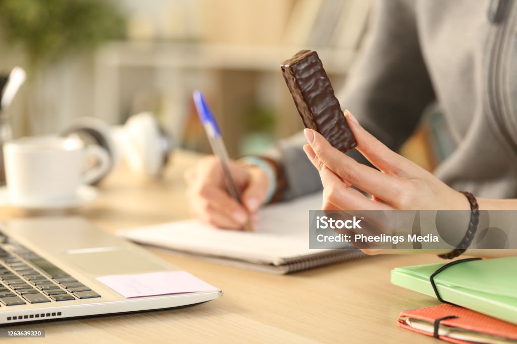 Student hands holding chocolate snack bar studying Chocolate Stock Photo