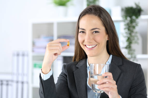 istock Happy executive shows pill and water glass at office 1263642098