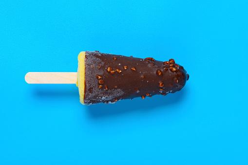 top view fresh vanilla flavor with chocoate and peanuts outer popsicle on a blue background