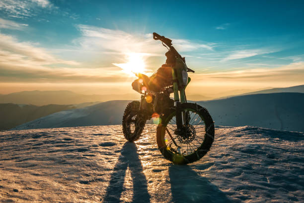 une moto avec des chaînes sur roues se tient au sommet d’une montagne en hiver - action off road vehicle motocross cycle photos et images de collection