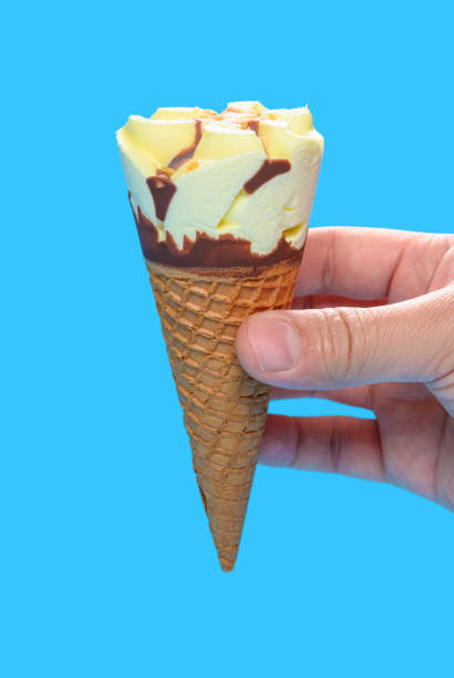 istock hand holding a fresh vanilla flavor ice cream cone on blue background 1263643610