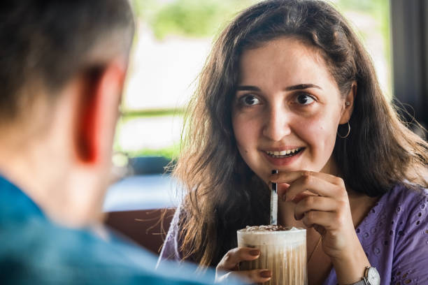 istock Young woman drinking coffee while talking to her friend 1263645243