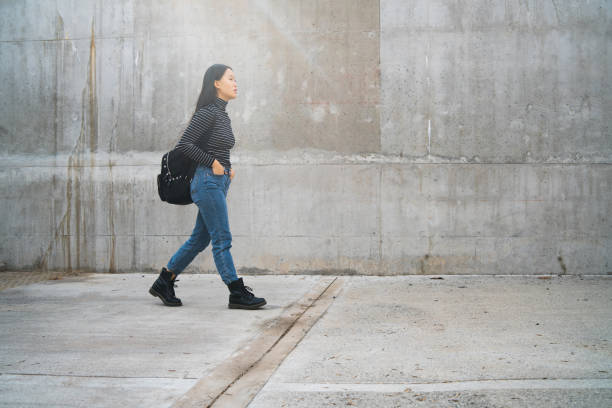 istock Asian woman walking against grey wall. 1263646350