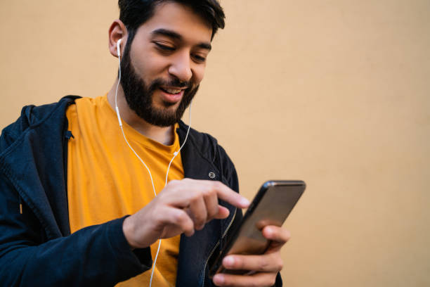 istock Latin man using his mobile phone with earphones. 1263646408