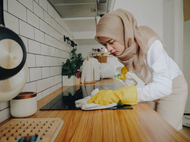 junge muslimische frau putzt ihre küchentheke zu hause - cleaning domestic kitchen counter top housework stock-fotos und bilder