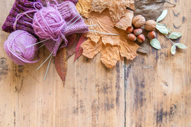 istock Knitting wool, knitting needles, leaves and nuts on wooden table 1263653167