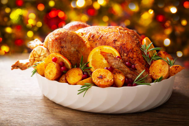 Christmas food. Baked turkey garnished with potato, oranges and  cranberries Christmas food. Baked turkey garnished with potato, oranges and  cranberries on a wooden table sauces table turkey christmas stock pictures, royalty-free photos & images