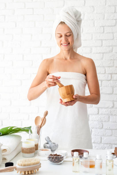 istock Happy young woman in white bathtowels using marble mortar and pestle doing spa procedures 1263658007