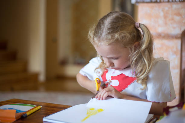 istock Little girl cuts out a drawing from a sketchbook. 1263658492
