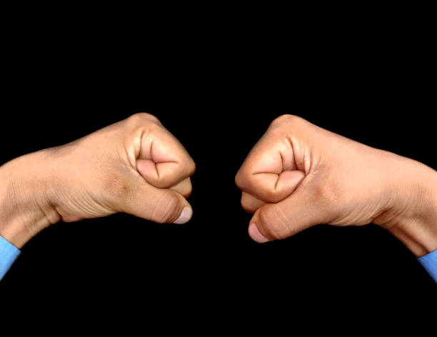 Hand fist opposite of another male hand fist wearing blue shirt, corporate opposition Concept, black background Hand Fist in front of another fist , strong opposition concept , Black background fist human hand punching power stock pictures, royalty-free photos & images