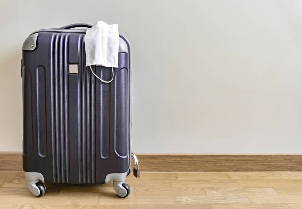 coronavirus mask for protection and black travel suitcase