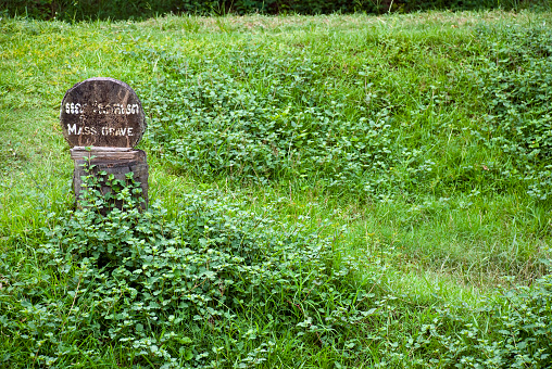 A wooden sign marks the site of a mass grave of victims of the Khmer Rouge, killed between 1975 and 1979, at Choeung Ek, located about 17 kilometers south of Phnom Penh, Cambodia. Choeung Ek is the most visited of the sites known as The Killing Fields; many of the 8,895 people killed here were political prisoners kept by the Khmer Rouge in their Tuol Sleng detention center in Phnom Penh.