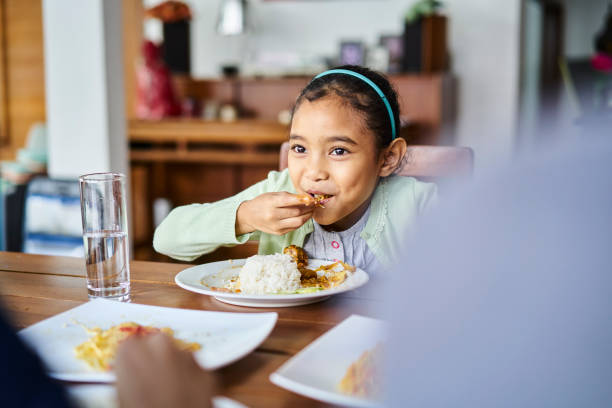 istock Cute little girl eating dinner at a table at home 1263670435