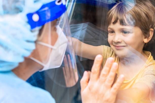 istock Mature Healthcare worker posing seeing her son with a window glass separating them to avoid possible contagion 1263672961