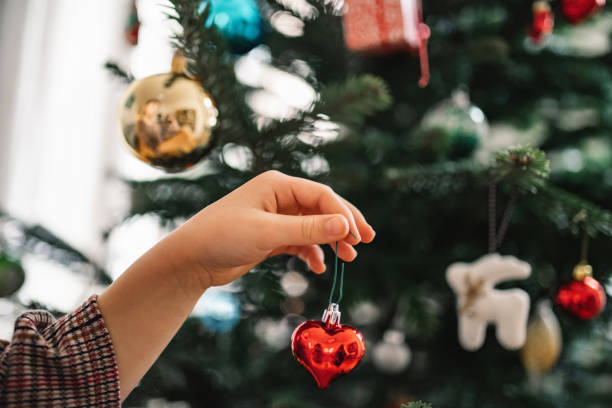 niña pequeña que decora árbol de navidad con corazón de cristal rojo - candle christmas tree candlelight christmas ornament fotografías e imágenes de stock