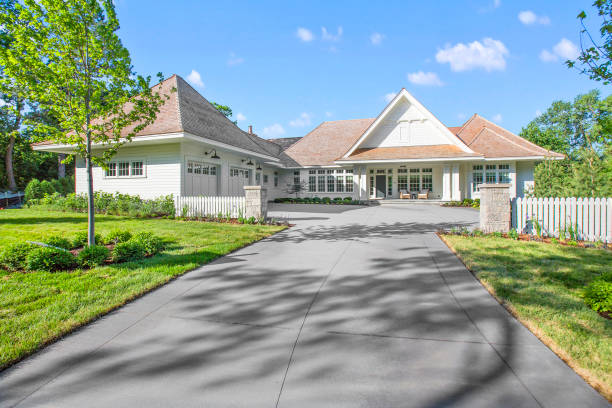 Newly constructed tour home with beautiful light colors for the roof and facade Two small pillars and picket fence give boundary and entrance to guests driveway photos stock pictures, royalty-free photos & images