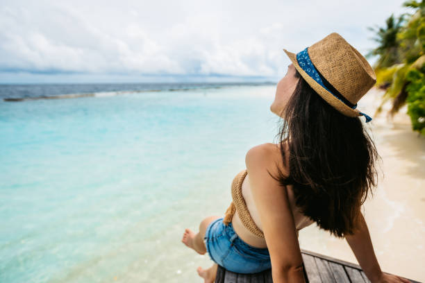 istock Woman sitting on pier over sea 1263685107