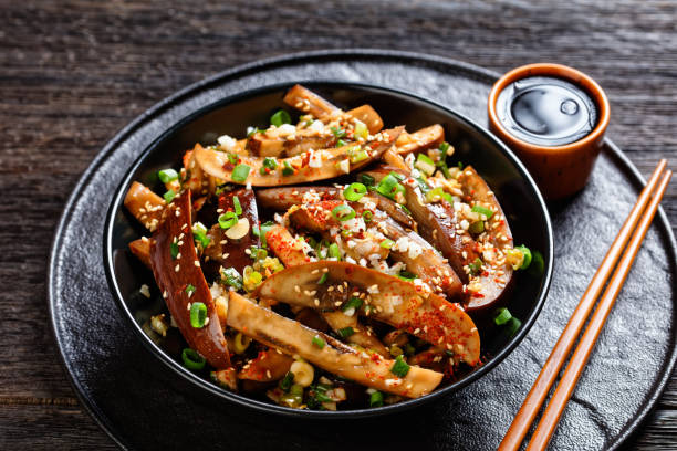 f Gaji Namul, steamed and seasoned eggplant Gaji Namul, steamed and seasoned eggplant in a black bowl on a wooden table with soy sauce and chopsticks, landscape view from above, close-up banchan stock pictures, royalty-free photos & images