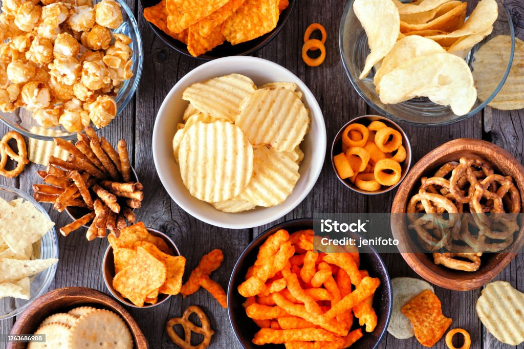 Mixed salty snack flat lay table scene on a wood background Mixed salty snacks. Flat lay table scene on a rustic wood background. Snack Stock Photo