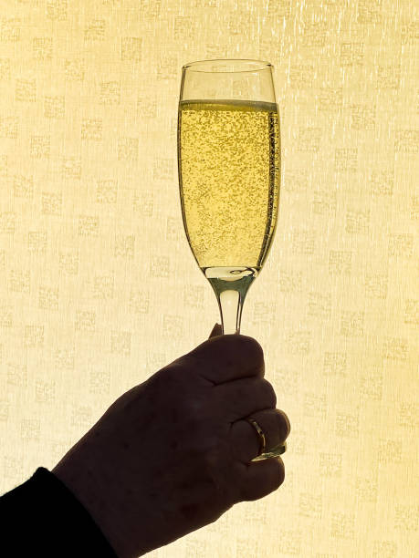 istock Flute glass of champagne held up against a plain background back lit by sunlight 1263689426
