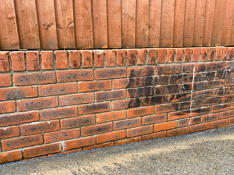 Brick wall being cleaned. Dirt and grime can be seen on the part which has not been pressure washed. No people. Copy space.