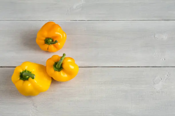 Shaped yellow bell peppers on the wooden white background. Misshapen produce, food waste problem concept. Trendy ugly food. Strange, imperfect organic vegetables. Horizontal, close up, top view