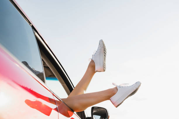 istock Female legs stick out from car window 1263693387