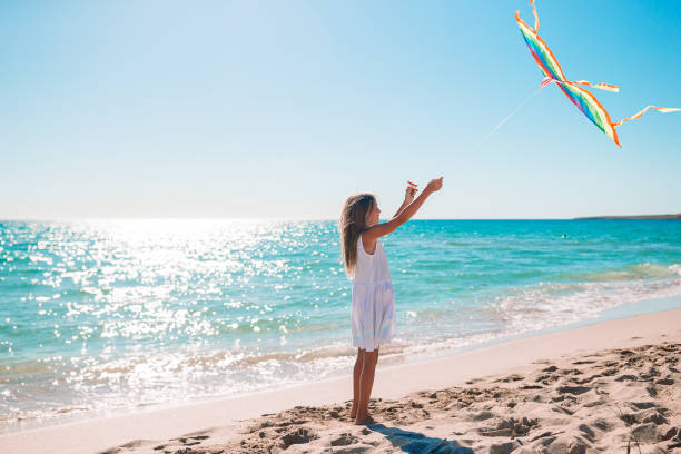 istock Little girl flying a kite on beach at sunset 1263694367