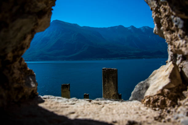 glimpse of lake garda among the rocks of the walls of the ancient lemon houses near Limone sul Garda, Brescia Italy