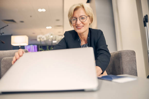 istock Cheerful blonde woman using notebook and smiling 1263696155