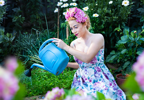 Portrait of fashionable woman in the garden with blossoming flowers.