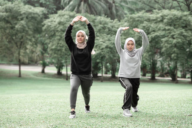 Beautiful muslim ladies doing exercise at a public park during a sunny day stock photo