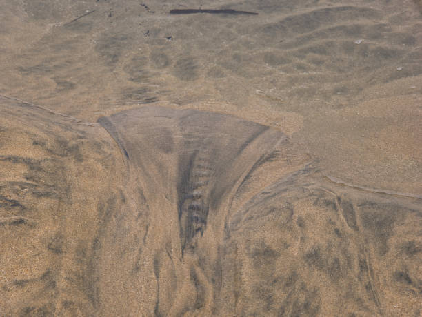 istock A funnel-shaped pattern in the black-brown sand 1263700604