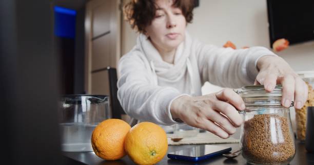 istock Woman is having breakfast with cornflakes and milk, instant coffee and fresh oranges 1263701364
