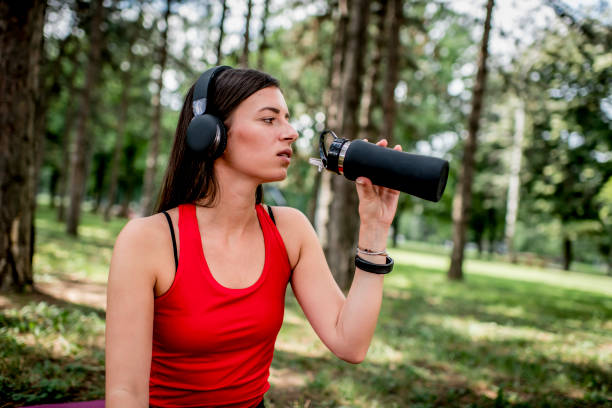 istock Young female athlete drinking water after training in the park 1263703574