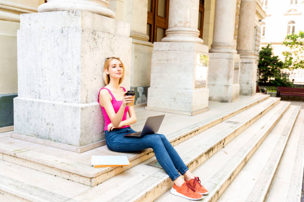 istock Young girl with laptop sitting on the stairs and using her laptop while learning 1263703709