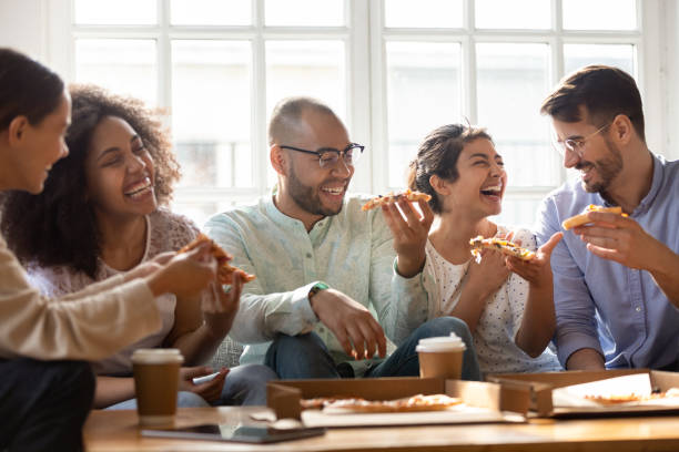 istock Five laughing multi-ethnic friends eating pizza indoors 1263705786