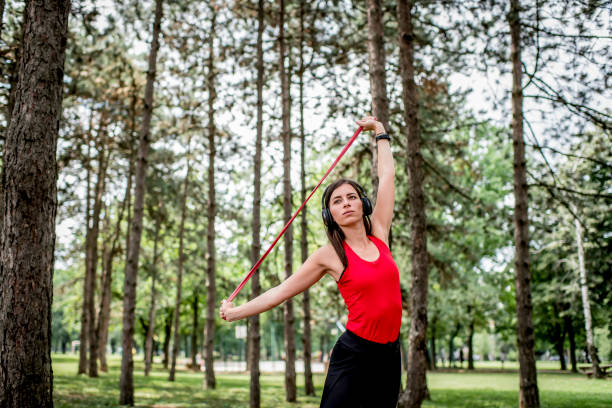 Young woman enjoying an outdoor workout, training on fitness equipment in a park on a sunny day.