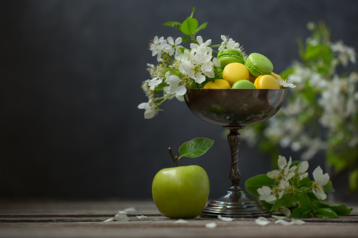 Macarons with apple flowers in a vintage vase. Still life in a retro style.